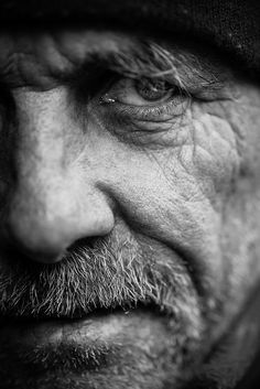 black and white photograph of an old man with beards looking at the camera, close up