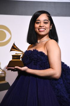 a woman in a blue dress holding an award for best female vocal performance at the 59th annual grammy awards