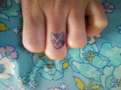 a person with a cat tattoo on their toe is laying next to a flowered sheet