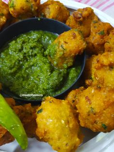 a white plate topped with fried food next to a green dipping sauce on top of it