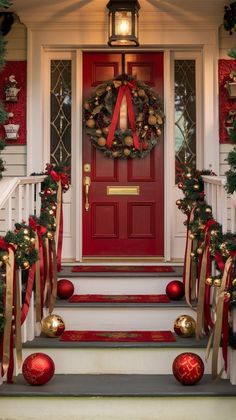 a red front door decorated for christmas with ornaments and wreaths on the steps leading up to it