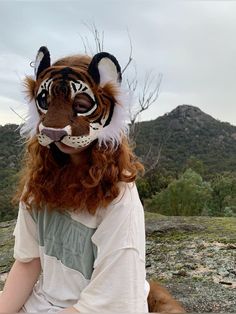 a person wearing a tiger mask sitting on the ground