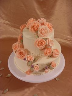 a three tiered wedding cake with pink roses on top