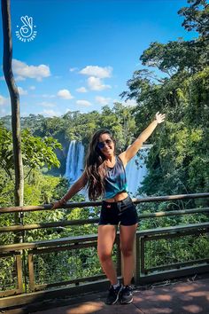 a woman standing in front of a waterfall with her arms spread out and hands outstretched