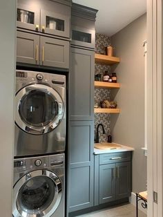 a washer and dryer in a small room with shelves on the wall behind them