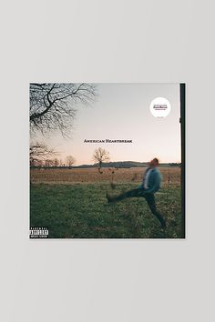 an album cover with a man running across a field in front of a bare tree