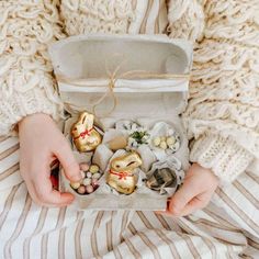 a woman is holding an open box filled with shells and seashells in it