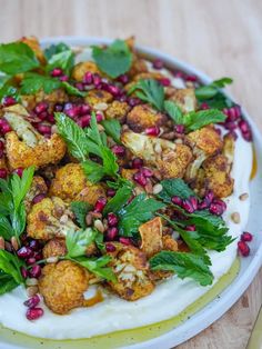 a white plate topped with cauliflower and pomegranate