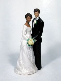 a bride and groom figurine standing next to each other on a white background