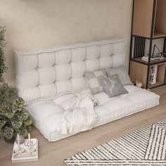 a white couch sitting on top of a wooden floor next to a potted plant