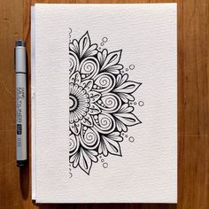 a notebook with a pen on top of it and a drawing of a flower in the middle