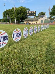 baseball signs are lined up on the grass in front of an empty ball field at a park