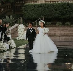 a young boy and girl are walking down the aisle