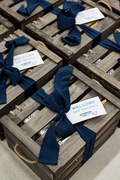 several wooden crates with blue ribbons tied around them and welcome cards attached to the lids