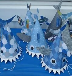 several paper shark hats on a blue table cloth with white polka dots and black stripes