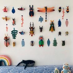 there are many different kinds of bugs on the wall above the bed and toys in front of it