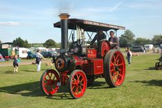 an old fashioned steam engine on display in a field with people standing around and looking at it