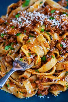 a blue plate topped with pasta covered in sauce and parmesan cheese