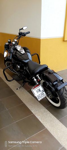 a black motorcycle parked in front of a yellow and white building with a license plate