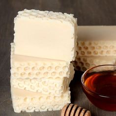 three pieces of soap next to a bowl of honey