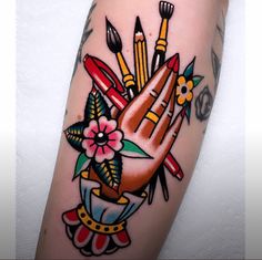 a person with tattoos on their arm and hand holding pencils, scissors, and flowers