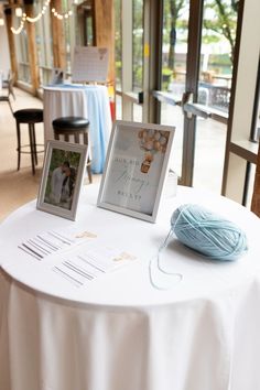 a white table topped with a ball of yarn and two pictures on top of it