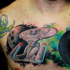 a man's chest with a star trek ship and planets tattoo on his chest