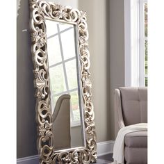 a large mirror sitting on top of a floor next to a chair