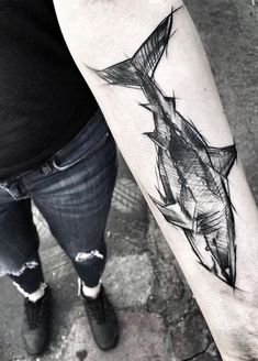 a black and white photo of a woman's arm with a fish tattoo on it