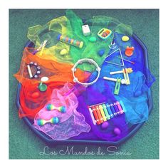 an assortment of toys and crayons on a play tray in the shape of a rainbow