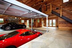 two red sports cars parked in a large garage with stairs leading up to the second floor