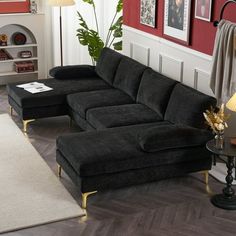 a living room with red walls and black couches in the corner, along with a white rug on the floor