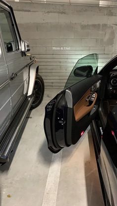 two cars parked in a garage next to each other and one has its door open