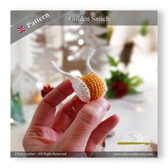 a hand holding a tiny crocheted snail in it's left hand with the word golden smith written below