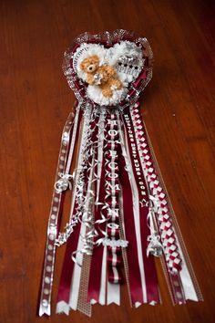 a teddy bear sitting on top of a red and white ribbon with silver ribbons around it