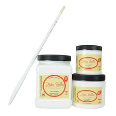 three jars of white candles with black lids and one jar filled with vanilla flavored sugar