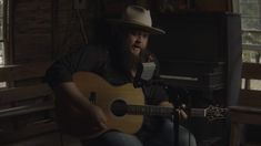 a man with a long beard is playing an acoustic guitar in front of a piano