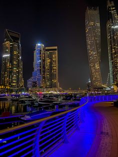 the city skyline is lit up at night with bright lights and boats in the water