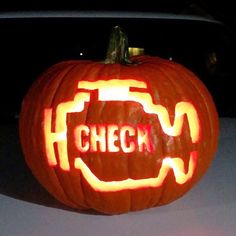 a carved pumpkin with the word check on it in front of a car at night