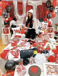 a woman standing in front of a table full of red and white items with balloons