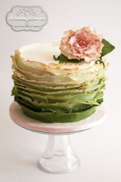 there is a cake with green and white frosting on the top, topped with a pink flower