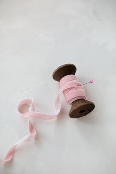 a spool of pink ribbon next to a wooden spool