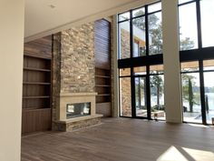 an empty living room with wood floors and large windows