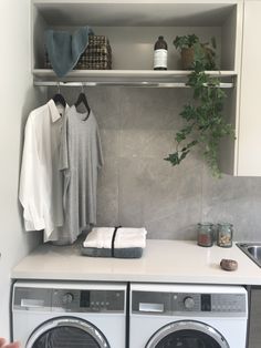 a washer and dryer in a small room with clothes hanging on the rack