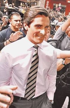 a man wearing a white shirt and black tie is surrounded by people in the street