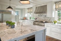 a large kitchen with marble counter tops and white cabinets, along with stainless steel appliances