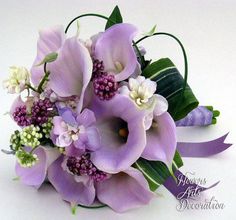 a bouquet of purple flowers and greenery on a white surface