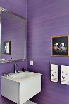 a bathroom with purple walls and white sink in front of a large framed painting on the wall