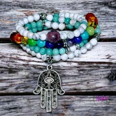 Welcome the Hamsa Chakra Healing Mala into your life! Be blessed with protection and equipped for healing with this beautiful 108 mala bead. With seven chakra stones and Amazonite, Howlite, and Turquoise accent stones all made of crystal, your spiritual security is guaranteed! The addition of Amethyst makes this piece especially powerful, - purifying your aura by removing any negative energy or feelings while grounding you in its powerful calming energy.But it doesn't stop there! This incredible White Beaded Bracelets With 108 Beads For Meditation, Spiritual Gemstone Beaded Bracelets For Festival, White Spiritual Hand Wrapped Beaded Bracelets, White Spiritual Hand-wrapped Beaded Bracelets, Turquoise Spiritual Beads For Meditation, Spiritual Turquoise Beads For Meditation, Symbolic Beaded Bracelets With Natural Stones For Meditation, White Spiritual Beaded Bracelets For Meditation, Spiritual Multicolor Beaded Bracelets