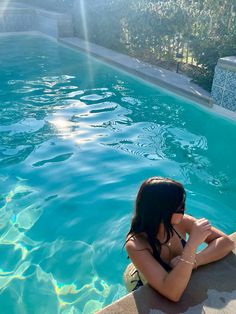 a woman sitting on the edge of a swimming pool